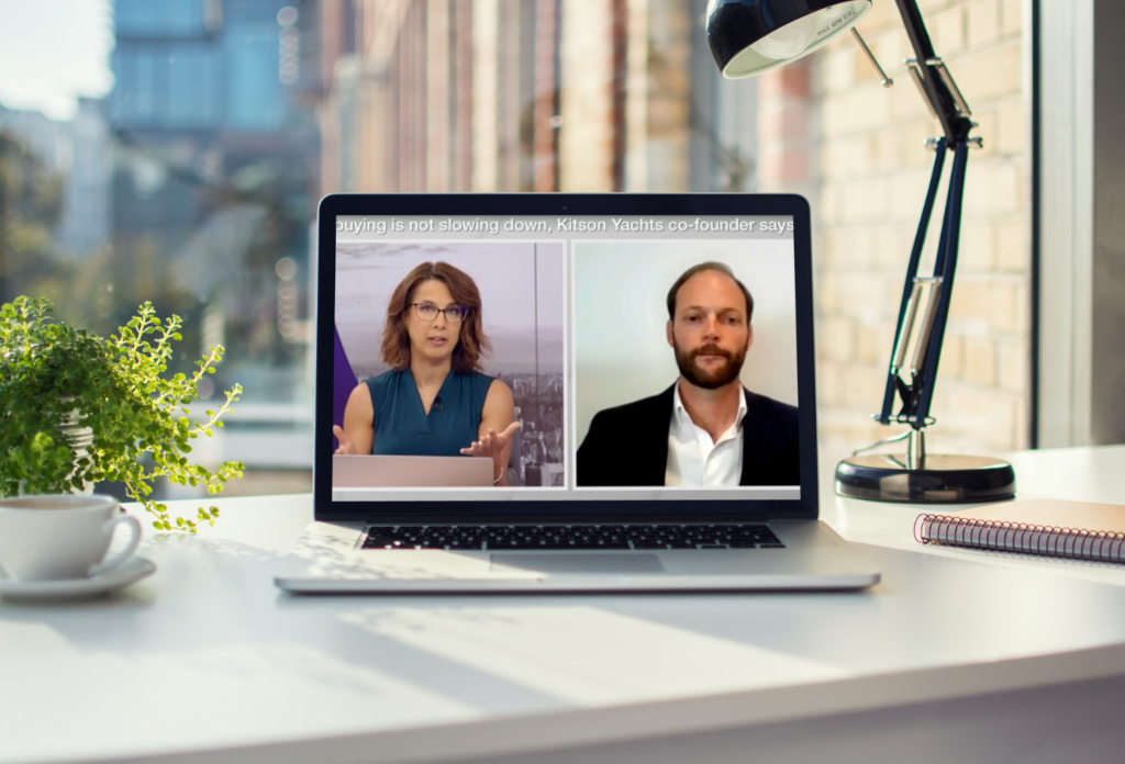 A laptop with two people on it and a coffee cup on it.