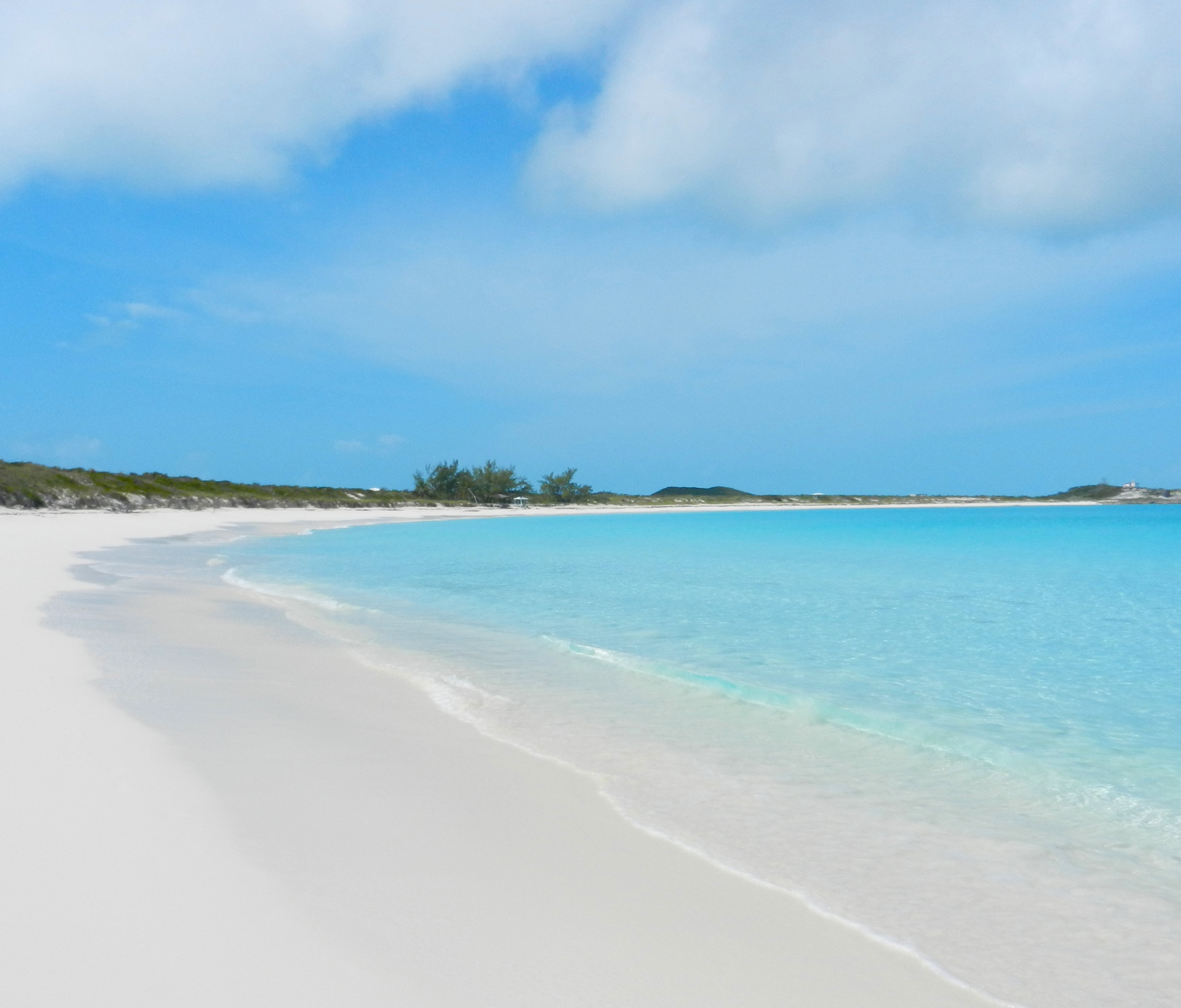 A beach with white sand and crystal blue water, perfect for Caribbean yacht charter destinations.