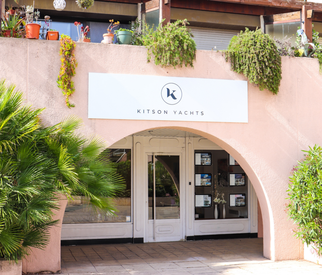 The entrance to a building adorned with lush plants and accompanied by an elegant sign, promising a Caribbean yacht charter in one of the most desirable destinations.